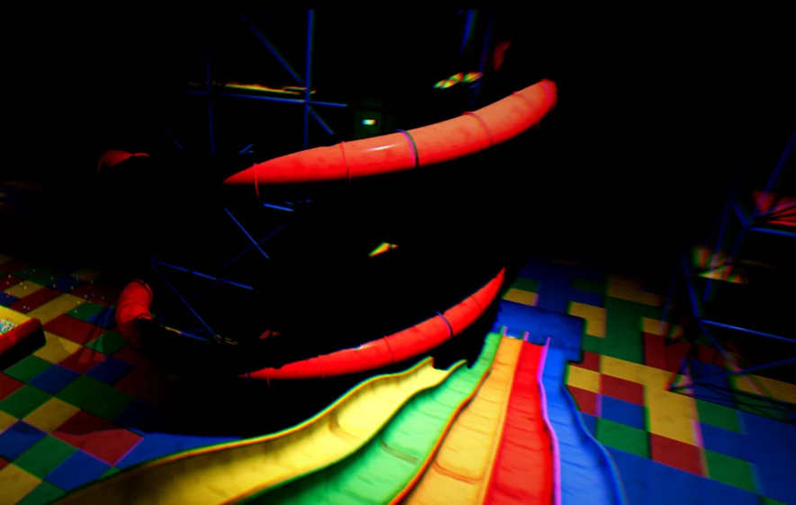 Red tube slides and rainbow wave slides inside a dark play structure.